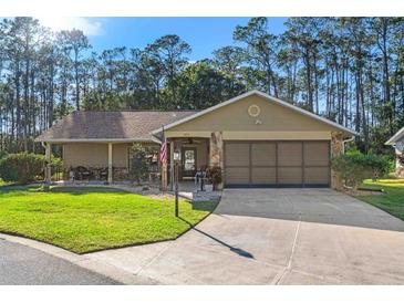 House exterior featuring a two-car garage and well-manicured lawn at 6312 Darien Way, Spring Hill, FL 34606