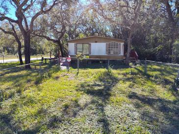 Mobile home with a fenced yard, situated on a spacious lot with mature trees at 12924 Manatee Ave, New Port Richey, FL 34654