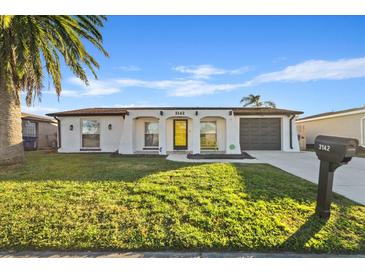 Newly renovated single-story home with a yellow door and landscaped lawn at 3142 Pinon Dr, Holiday, FL 34691