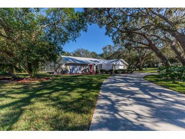 Single-story home with a stone facade, long driveway and mature trees at 7256 Royal Oak Dr, Spring Hill, FL 34607