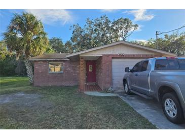 Brick ranch house with red door, attached garage, and a truck parked in the driveway at 8030 Gulf Way, Hudson, FL 34667