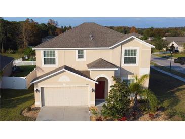 Two-story house with a red door, attached garage, and landscaping at 10167 Bankston Dr, Hudson, FL 34667