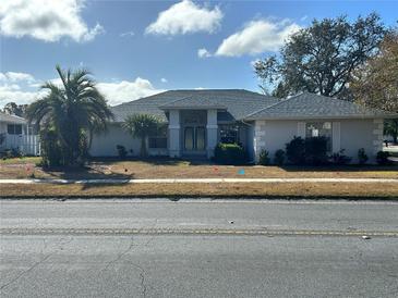 Charming single-story home with a gray tiled roof and landscaped front yard at 1230 Ambrose Ct, Spring Hill, FL 34608