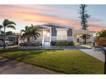 Newly constructed manufactured home with gray siding, landscaping, and a covered carport at 1852 Cypress Point Ln, Sarasota, FL 34234