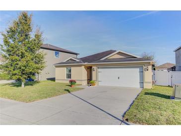 Tan one-story house with a white garage door at 4148 Sand Ridge Blvd, Spring Hill, FL 34609