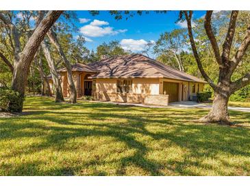 Charming single-Gathering home with a brown roof, brick accents, and a lush green lawn at 7443 Oak Tree Ln, Spring Hill, FL 34607