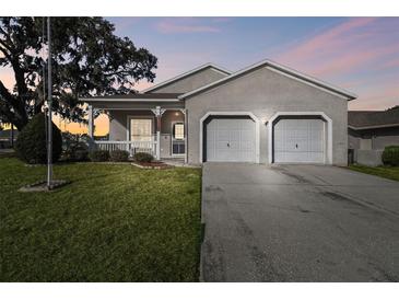 Charming single-story home with two-car garage and landscaped front yard at dusk at 12415 Willow Tree Ave, Hudson, FL 34669