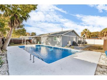 A backyard view of a refreshing in-ground swimming pool surrounded by a concrete patio in a private backyard at 15950 Adobe Dr, Hudson, FL 34667