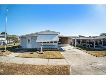 Light blue manufactured home with carport and landscaped yard at 3844 Kim Dr, Wesley Chapel, FL 33543