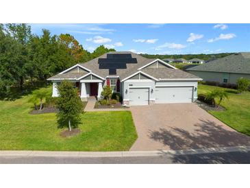 Single-story home with solar panels, three-car garage, and landscaped yard at 19771 Tattnall Way, Brooksville, FL 34601