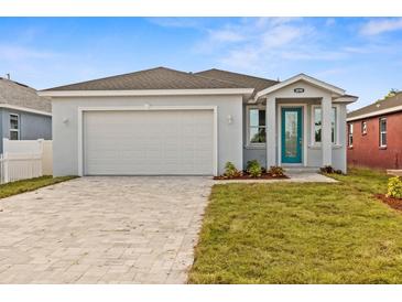 Newly constructed home with a teal front door and paver driveway at 8290 40Th N St, Pinellas Park, FL 33781