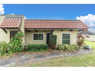 Inviting condo exterior with a terracotta tile roof and well-manicured landscaping at 1701 Pinehurst Rd # 9-H, Dunedin, FL 34698