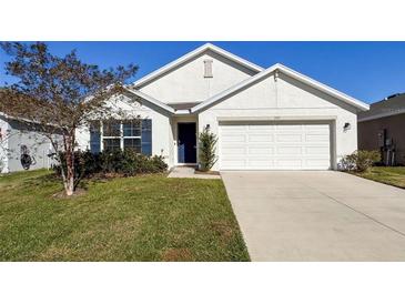 White house with blue door, two-car garage, and well-manicured lawn at 3337 Autumn Amber Dr, Spring Hill, FL 34609