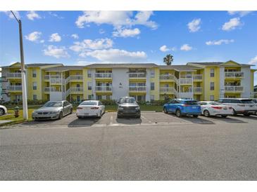 Front view of a yellow condo building with ample parking at 455 Alt 19 S # 163, Palm Harbor, FL 34683
