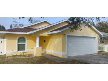 House exterior featuring a yellow stucco exterior, attached garage, and mature landscaping at 5031 6Th N Ave, St Petersburg, FL 33710