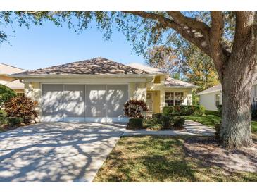 Charming single-story home with attached two-car garage, landscaped front yard, and mature shade tree at 14120 Whitecap Ave, Hudson, FL 34667