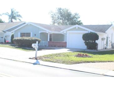 House exterior featuring light teal siding, brick accents, and a two-car garage at 3518 Moog Rd, Holiday, FL 34691