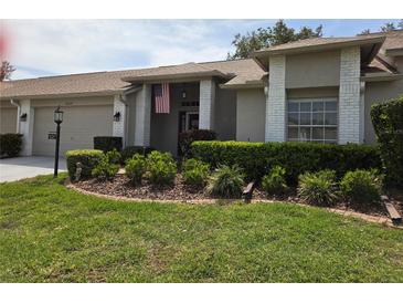 Charming single-story home featuring a well-manicured lawn, an American flag, and a neatly landscaped garden at 18049 Tarrington Pl, Hudson, FL 34667