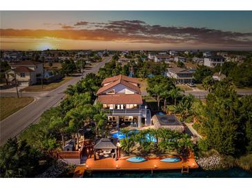 Stunning waterfront home featuring a private dock, pool, and lush tropical landscaping at sunset at 3308 Oleander Dr, Hernando Beach, FL 34607