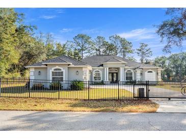 Beautiful single-story home featuring a black iron fence, well-manicured lawn, and a modern architectural design at 7482 Winter St, Brooksville, FL 34613