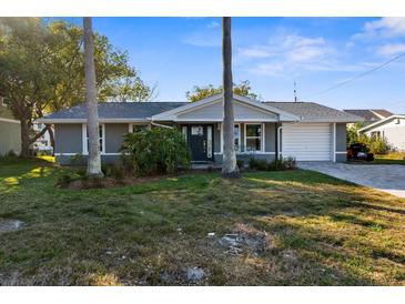 Charming single-story home with a manicured front yard, an attached garage, and a welcoming entrance at 8225 Channel Dr, Port Richey, FL 34668
