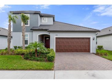 Inviting two-story home showcasing a well-manicured lawn and a brick paved driveway to the two-car garage at 17026 Shell Bay Dr, Land O Lakes, FL 34638