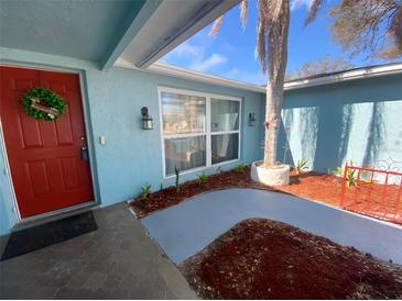 Charming home with a red front door, palm tree, and blue exterior paint at 1817 Dartmouth Dr, Holiday, FL 34691