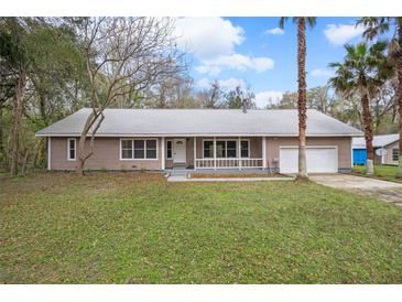 Charming single-story home featuring a welcoming front porch, attached garage and mature landscaping at 13289 Joy Path, Brooksville, FL 34601