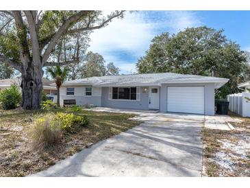 Charming single story home featuring mature trees, a front yard, and a one car garage at 686 Manor W Dr, Dunedin, FL 34698
