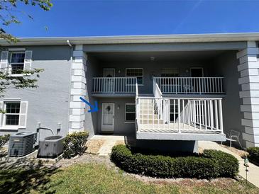 A clean, grey two-story condo building with a white railing on the porch and well-maintained landscaping at 12027 Hoosier Ct # 104, Hudson, FL 34667