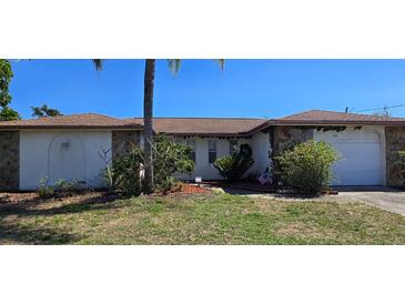 Charming single-story home featuring stone accents, lush landscaping, and a well-maintained front yard at 1414 Grand Blvd, Holiday, FL 34690
