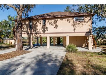 Charming raised home showcasing a neutral stucco exterior, carport and convenient access stairs at 12724 Circle Lake Dr, Hudson, FL 34669