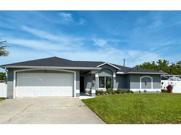 Charming single-story home boasts a well-manicured lawn, two-car garage, and sleek gray paint scheme at 5801 65Th N Ter, Pinellas Park, FL 33781