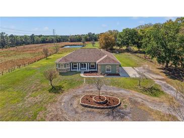 Inviting single-story home features lush landscaping, long driveway, and charming pond view at 6413 Emerson Rd, Brooksville, FL 34601