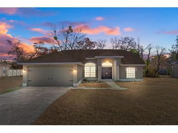 Charming single Gathering home with neutral paint, attached garage, and traditional landscaping at 2124 Godfrey Ave, Spring Hill, FL 34609