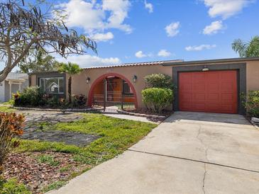 Single story home featuring stucco exterior, red garage door, archway entry, and mature landscaping at 3730 Sail Dr, New Port Richey, FL 34652