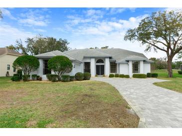 Charming single-story home featuring a well-manicured lawn and long paved driveway at 9397 Merriweather Dr, Weeki Wachee, FL 34613