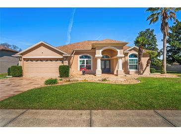 Charming single-story home with manicured lawn, arched entry, and attached two-car garage at 14251 Mansfield Rd, Spring Hill, FL 34609