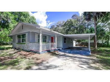 Charming single-story home features a covered carport and quaint front porch with red accents at 406 Zoller St, Brooksville, FL 34601
