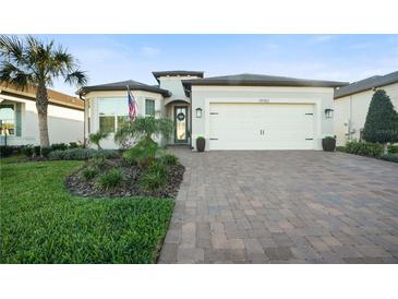 Charming single-story home featuring a well-manicured lawn, paver driveway, and an attached two-car garage at 19742 Sea Glass Cir, Land O Lakes, FL 34638