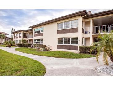 Well maintained two-story condo building featuring tan stucco walls, brown accents, and lush, landscaped surroundings at 4712 Marine Pkwy # 104, New Port Richey, FL 34652