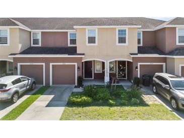 Charming two-story townhome featuring a one-car garage, front lawn, and neutral color scheme at 7030 Woodchase Glen Dr, Riverview, FL 33578