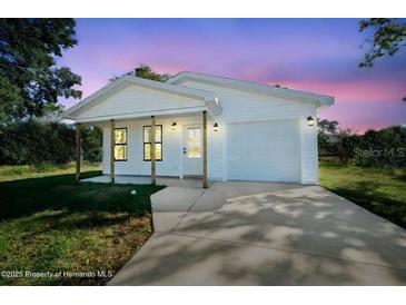 Charming one-story white home with a covered porch and an attached one-car garage at 14356 Earline Rd, Brooksville, FL 34614