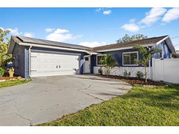 Charming blue home featuring solar panels, a spacious driveway, and well-maintained landscaping at 5590 77Th N Ave, Pinellas Park, FL 33781