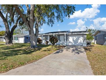 Charming single-story home with a well-manicured lawn, gray paint, white trim and an attached garage at 10841 Scenic Dr, Port Richey, FL 34668