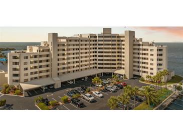 A large condo building near the water features covered parking, palms, and nice landscaping at 6035 Sea Ranch Dr # 408, Hudson, FL 34667