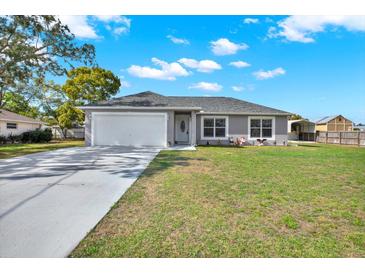 Charming single-story home featuring a well-maintained lawn, attached two-car garage, and long private drive at 7205 Pinehurst Dr, Spring Hill, FL 34606