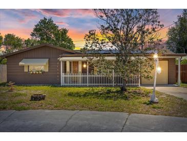 Charming single-story home featuring brown siding, a cozy front porch, and a well-maintained lawn at sunset at 3728 Linkwood St, New Port Richey, FL 34652