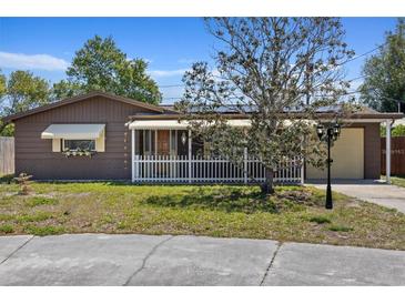 Charming single-story home featuring a white picket fence, covered porch, and well-maintained yard, creating inviting curb appeal at 3728 Linkwood St, New Port Richey, FL 34652