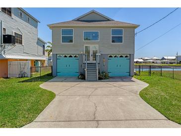 Two-story home featuring a two-car garage with blue doors and a well-maintained front yard at 4046 Casa Ct, Hernando Beach, FL 34607